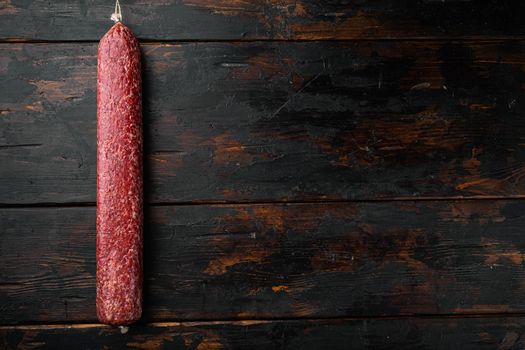 Traditional smoked salami sausage set, on old dark wooden table background, top view flat lay, with copy space for text