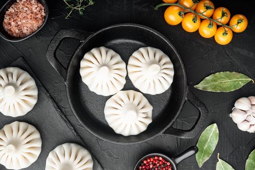 Khinkali, Georgian dumplings, traditional Georgian cuisine set, in frying cast iron pan, on black stone background, top view flat lay