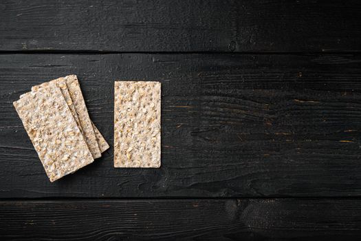 Crisp bread with sunflower, chia and sesames seeds set, on black wooden table background, top view flat lay, with copy space for text