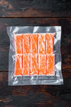 Crab sticks in vacuum pack set, on dark wooden background, top view flat lay