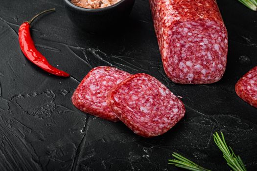 Salami, salami smoked sausage, sliced set, on black dark stone table background, with copy space for text