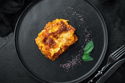 Italian Lasagne with tomato bolognese sauce and mince beef meat set, on plate, on black stone background, top view, flat lay