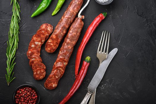 Spanish chorizo sausage slices with herbs and spices on balck background, top view with copy space.