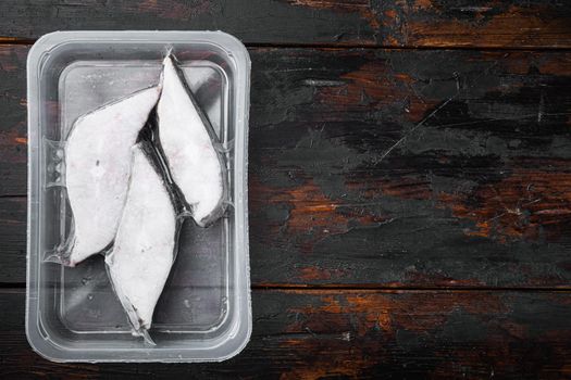 Raw fillets frozen halibut airtight vacuum pack set, on old dark wooden table background, top view flat lay, with copy space for text
