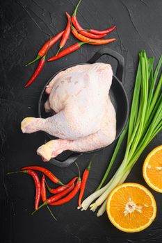 Sticky hoisin chicken ingredients set, with orange and chili, on frying cast iron pan, on black stone background, top view flat lay