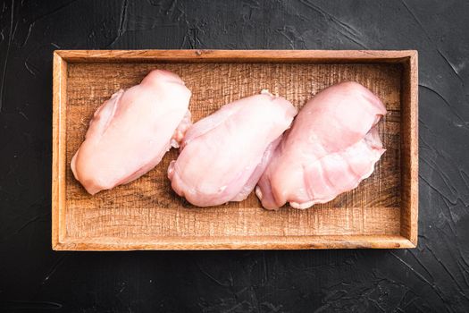 Fresh chicken meat set, in wooden box, on black stone background, top view flat lay
