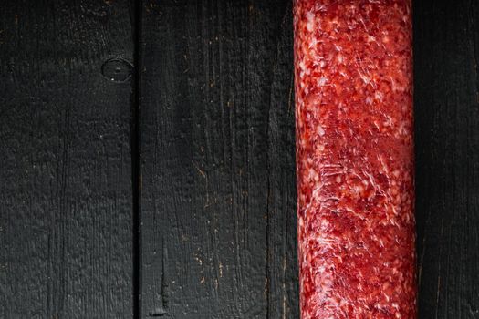 Fresh salami set, on black wooden table background, top view flat lay, with copy space for text