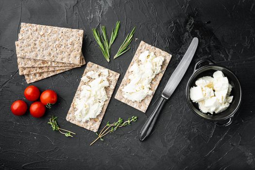 Curd sandwiches with fresh herbs. Crispbread toast with cottage cheese set, on black dark stone table background, top view flat lay