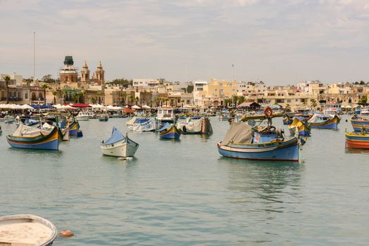 Traditional eyed colorful boats Luzzu in the Harbor of Mediterranean fishing village Marsaxlokk, Malta