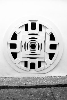 Circular wooden door with black iron details  and whitewashed facade in Altea, Alicante, Spain.