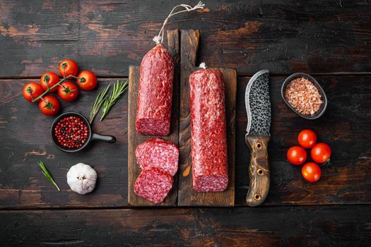Salami with fresh rosemary and spices set, on old dark wooden table background, top view flat lay