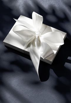 Anniversary celebration, shop sale promotion and luxe surprise concept - Luxury holiday white gift box with silk ribbon and bow on black background, luxe wedding or birthday present