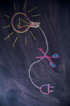 Graphic representation of the concept of electricity savings, drawn with chalk on blackboard