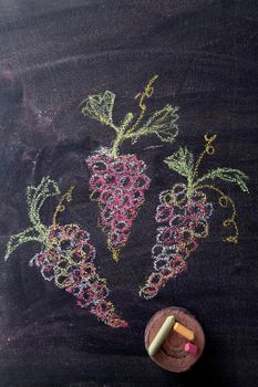 Representation with chalk on blackboard three bunches of red grapes