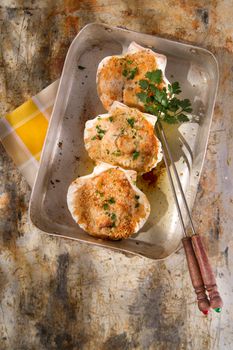 Presentation of scallops au gratin baked with parsley