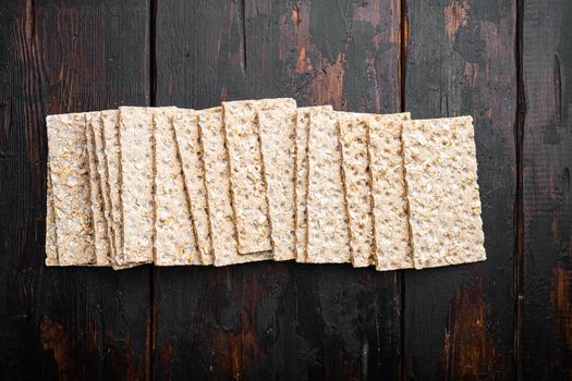 Whole grain crisp bread set, on old dark wooden table background, top view flat lay, with copy space for text
