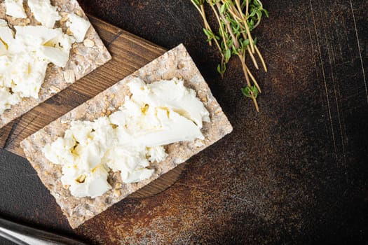 Crispbreads with feta set, on old dark rustic table background, top view flat lay, with copy space for text