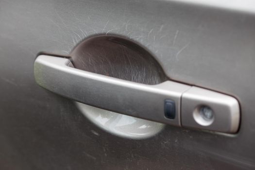 nail scratches on paint of car door handle - close-up with selective focus