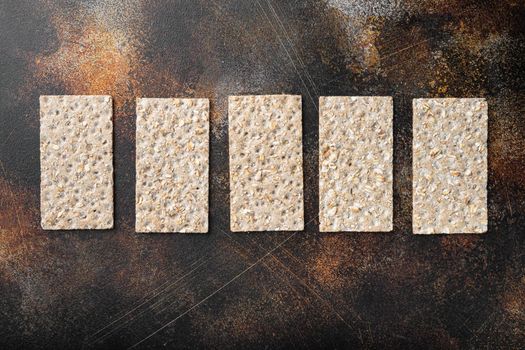 Whole grain crisp bread set, on old dark rustic table background, top view flat lay, with copy space for text