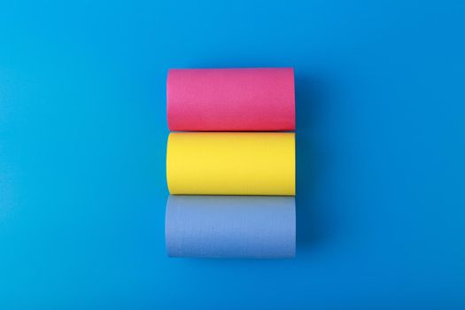 Flat lay with pansexual flag made of pink, yellow and blue rolls on blue background. Concept of pansexual community, sexual minorities, equal right and tolerance
