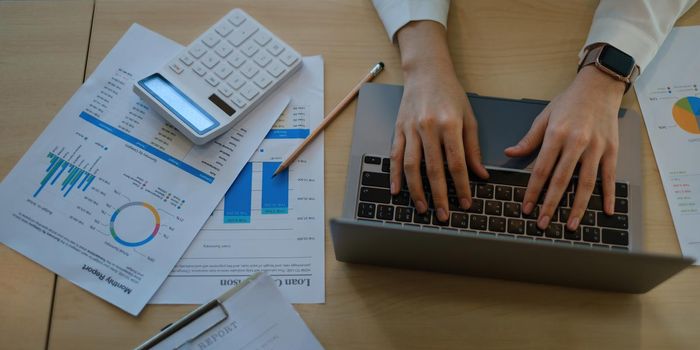 Business woman trader investor using laptop with paperwork stock market graph on desk. stock chart, investment concept