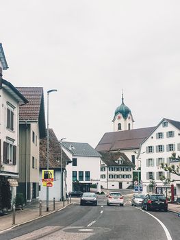 Wollerau, canton of Schwyz, Switzerland circa June 2021: Historic buildings, church and houses on street, Swiss architecture and real estate