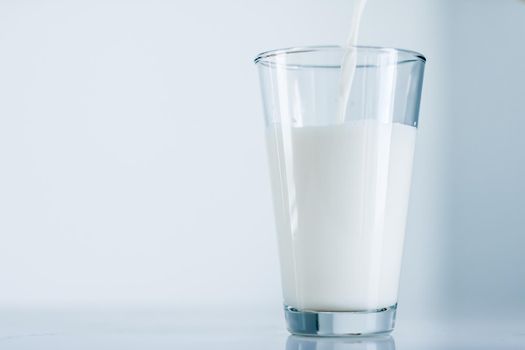 Dairy, healthy nutrition and breakfast concept - World Milk Day, pouring into glass on marble table