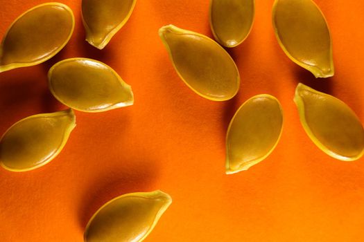 Fresh goliath pumpkin seeds abstract close-up layout on orange, South Africa