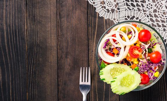 Top view of the healthy colorful fresh salad bowl with quinoa, tomatoes, and mixed greens vegetable in a dish on black wooden background, Health snack food