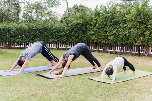 Asian young mother, father practicing doing yoga exercises with child daughter outdoors in meditate pose together in nature a field garden park, family kid sport and exercises for healthy lifestyle