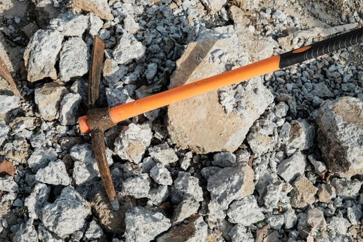 pickaxe hoe lying on crushed stones. hand-held percussion tool designed for working on stone, stony ground, very dense ground.