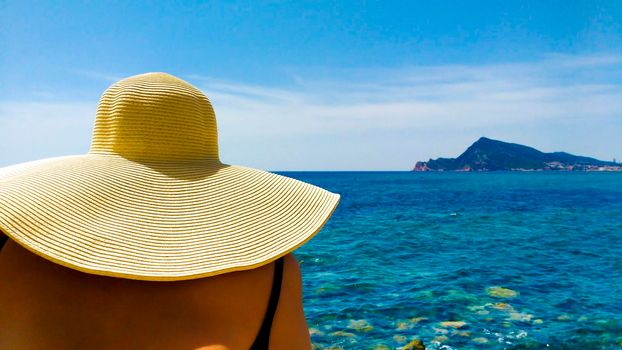 Woman in big white on Cap Negret beach on a sunny day of Spring in Altea, Alicante, Spain
