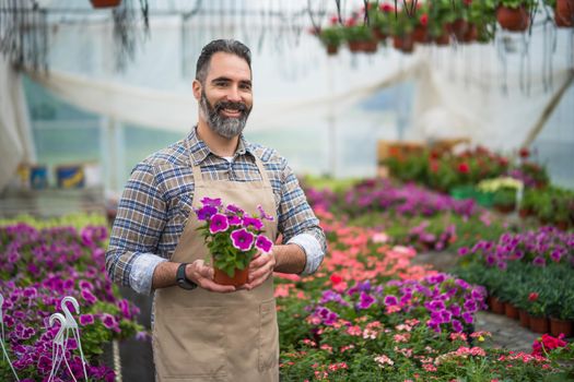 Mid adult man is owning small business greenhouse store.