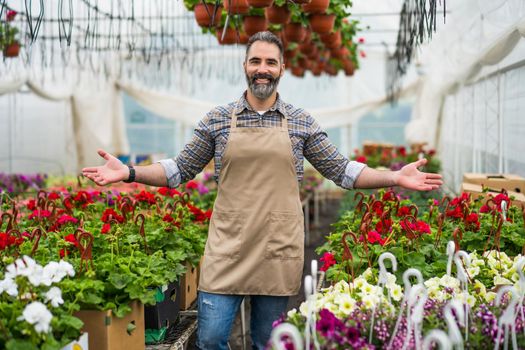 Adult man is owning small business greenhouse store.