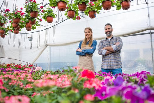 Happy couple is owning small business greenhouse store.