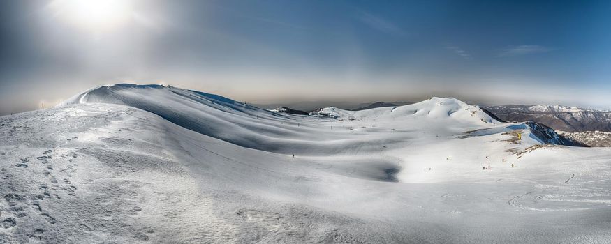 Scenic panoramic winter landscape with snow covered mountains, located in Campocatino, touristic ski town in the Central Apennines, Italy