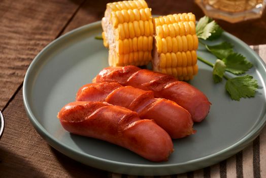 Home grilled sausages on a dark plate, a meat dish on a dark wooden background, hot sausages with spices and salt in a home kitchen, copy space, rustic style, art