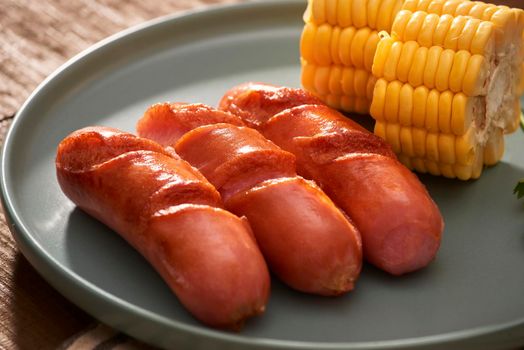 Home grilled sausages on a dark plate, a meat dish on a dark wooden background, hot sausages with spices and salt in a home kitchen, copy space, rustic style, art