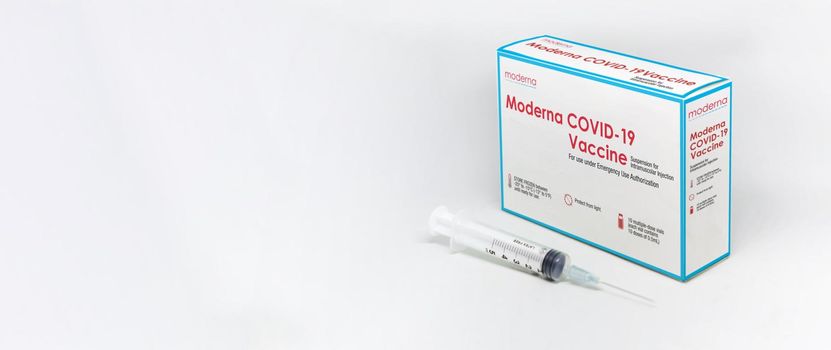 Cambridge, MA, USA, february 5th 2021: A syringe next to the ModeRNa Covid-19 vaccine box isolated on a white background. Health and prevention.