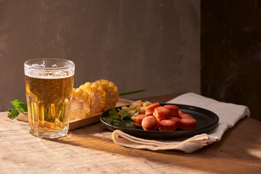 Grilled sausages with glass of beer on wooden table with copy space.