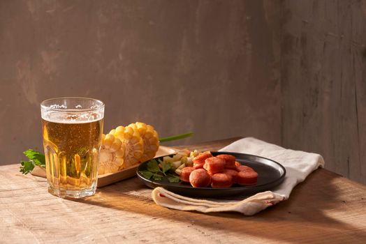 Grilled sausages with glass of beer on wooden table with copy space.