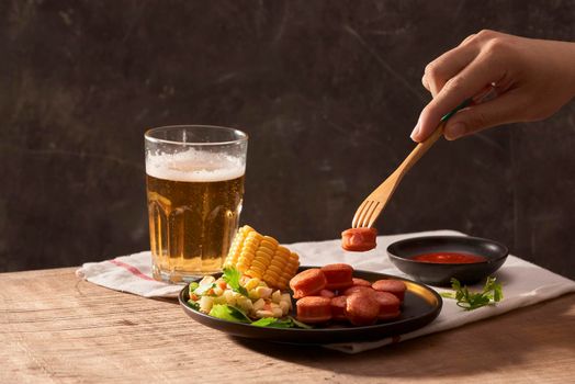 Man eating sliced sausages with salad and having wheat beer