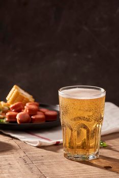 Beer and appetizing beer snacks set. Table with mug beer grilled sausages with sauces.