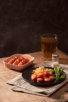 Glass of delicious beer with grilled sausages on wooden table