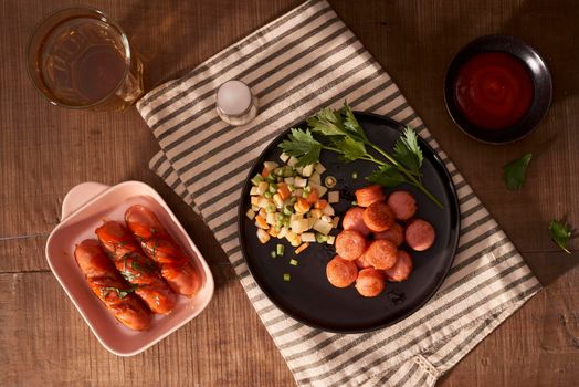 Glass of delicious beer with grilled sausages on wooden table