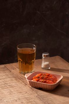 Glass of delicious beer with grilled sausages on wooden table