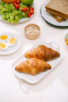 Healthy Breakfast served with milk, croissants, egg, cereals, oatmeal and fruits.