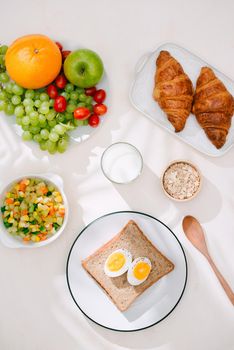 Healthy Breakfast served with milk, croissants, egg, cereals, oatmeal and fruits.