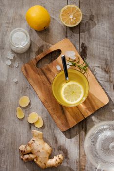 Cup of Ginger tea with lemon. Cup of Ginger tea with lemon. Glass mug of green hot tea on wooden table. Sliced lemons on a chopping board