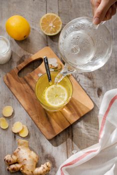 Cup of Ginger tea with lemon. Cup of Ginger tea with lemon. Glass mug of green hot tea on wooden table. Sliced lemons on a chopping board